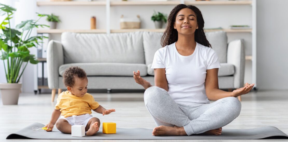Mental Wellness Concept. Calm Happy Black Mother Meditating With Baby At Home
