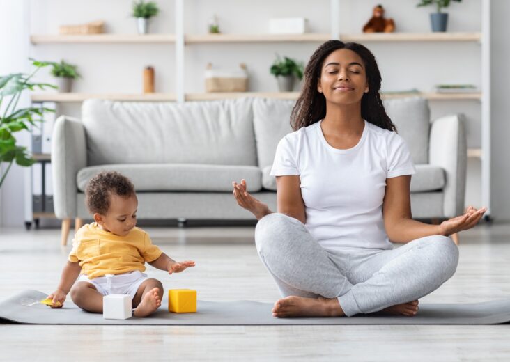 Mental Wellness Concept. Calm Happy Black Mother Meditating With Baby At Home