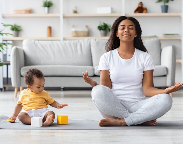 Mental Wellness Concept. Calm Happy Black Mother Meditating With Baby At Home