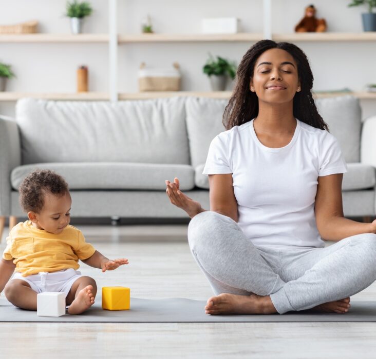 Mental Wellness Concept. Calm Happy Black Mother Meditating With Baby At Home