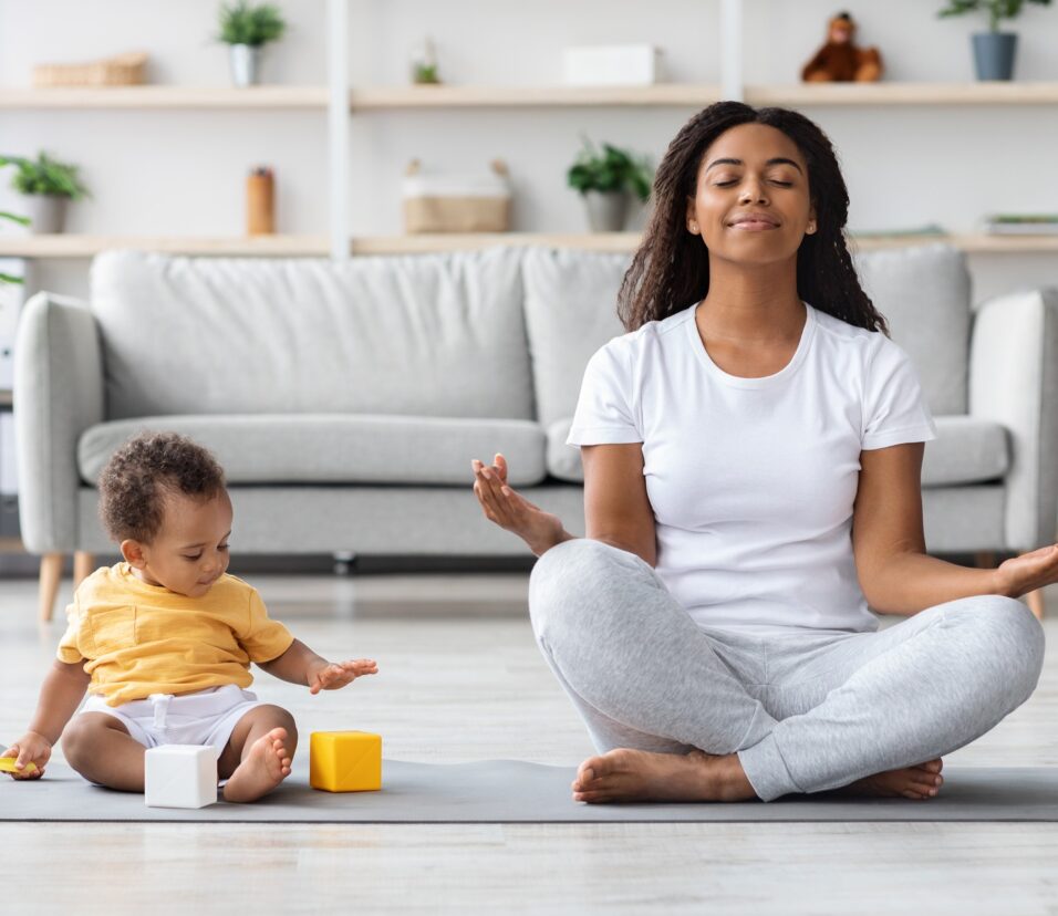 Mental Wellness Concept. Calm Happy Black Mother Meditating With Baby At Home