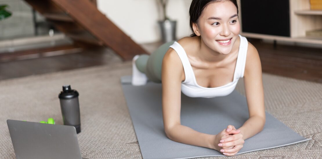 Sporty asian girl in activewear doing workout at home, follow video sport guide, online fitness