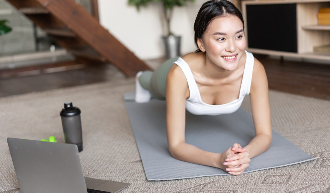 Sporty asian girl in activewear doing workout at home, follow video sport guide, online fitness