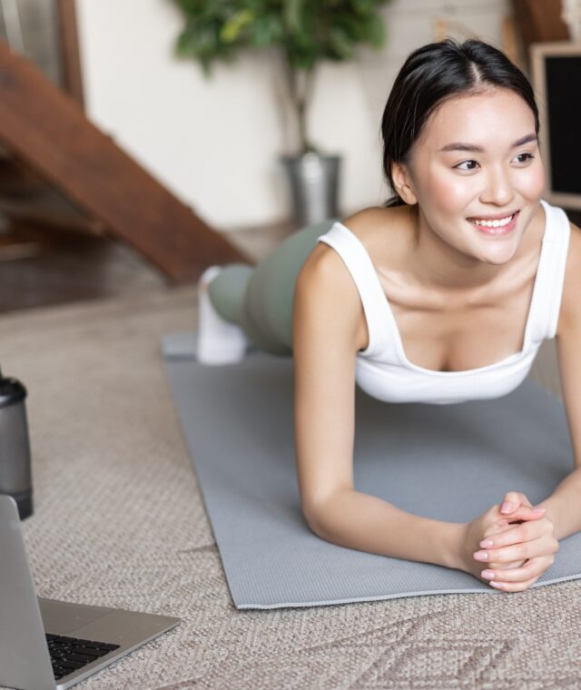 Sporty asian girl in activewear doing workout at home, follow video sport guide, online fitness