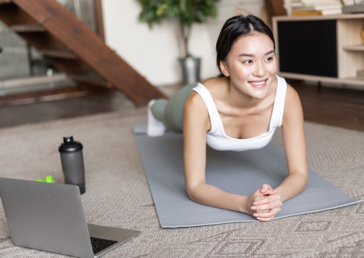 Sporty asian girl in activewear doing workout at home, follow video sport guide, online fitness