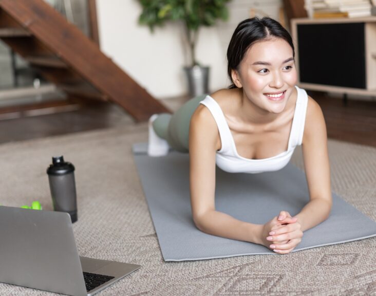 Sporty asian girl in activewear doing workout at home, follow video sport guide, online fitness