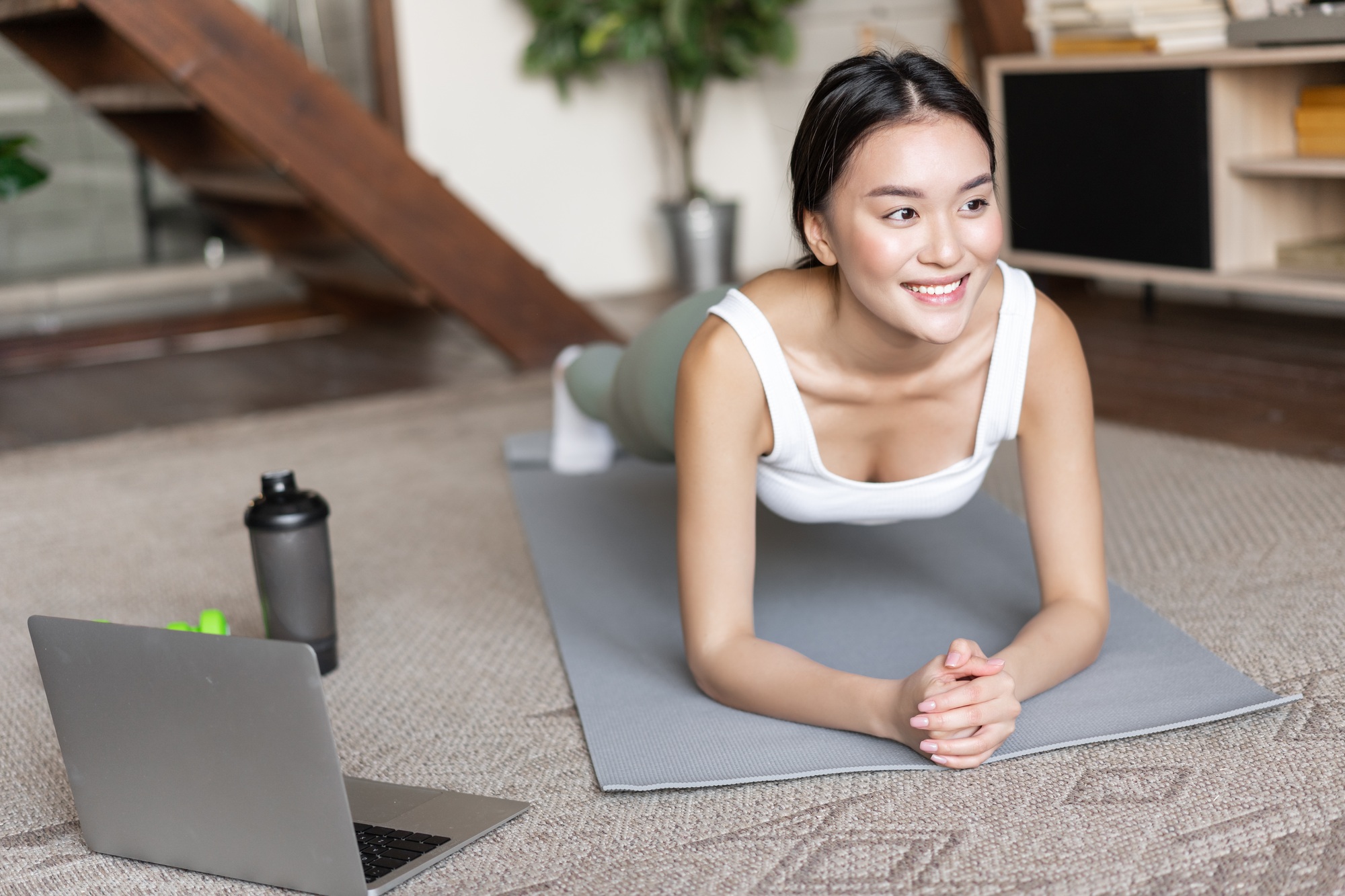Sporty asian girl in activewear doing workout at home, follow video sport guide, online fitness