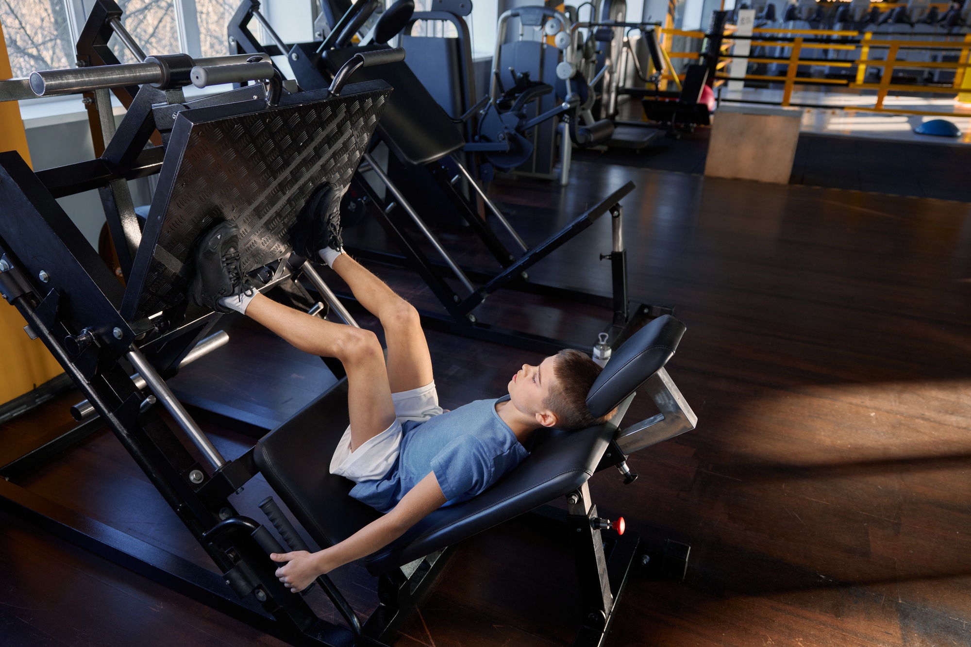 Teenage boy training legs at platform press strength machine